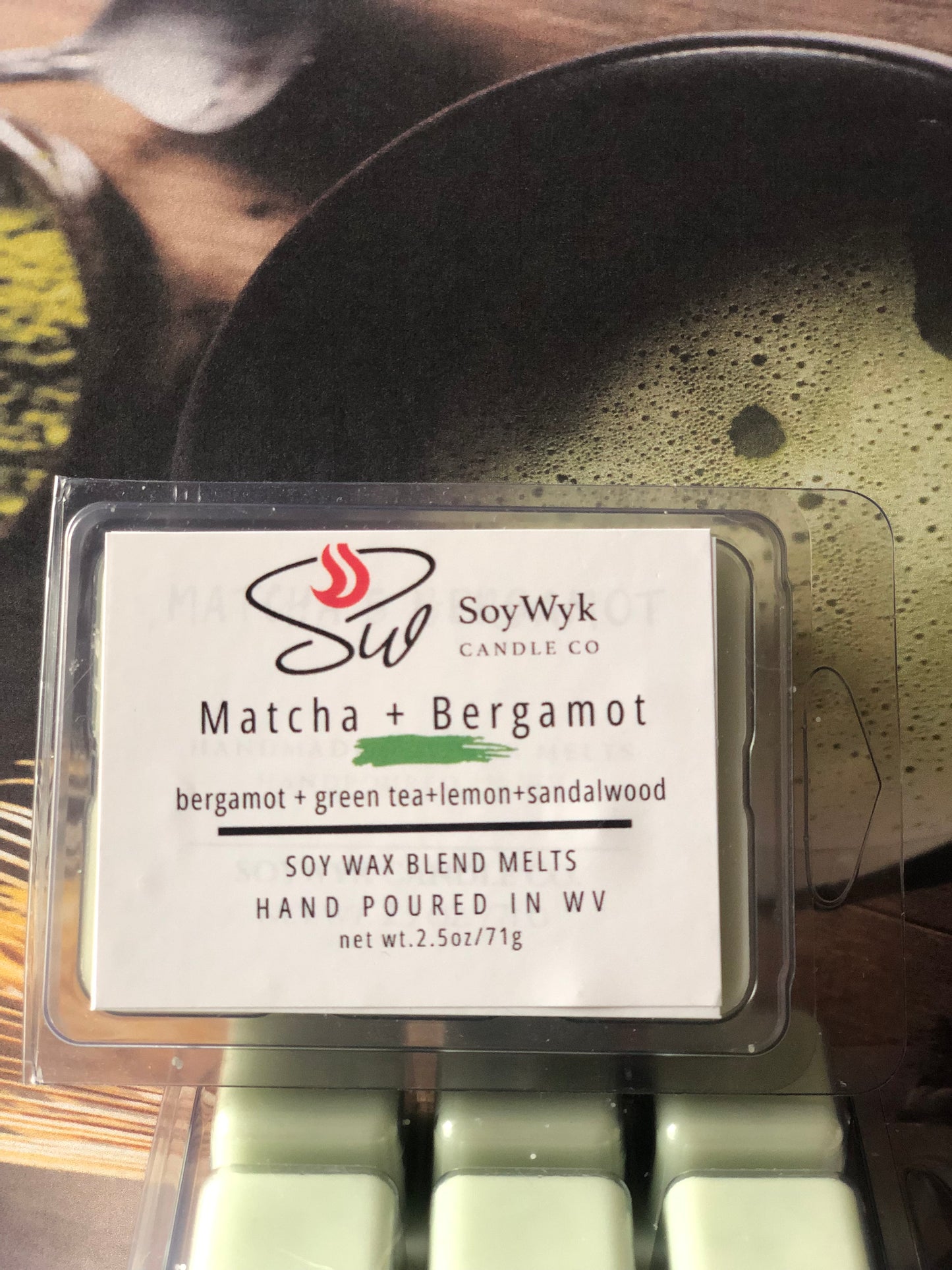 White Soy Wax Melt in a 2.5 oz clear package.  The wax melt is on a wood table with a large black matcha tea bowl and a wood matcha tea stirring whisk. Labeled as “Matcha & Bergamot”. 
Featured fragrant notes are bergamot, green tea, lemon, sandalwood. 
Hand-poured in WV by SoyWyk Candle Co. 