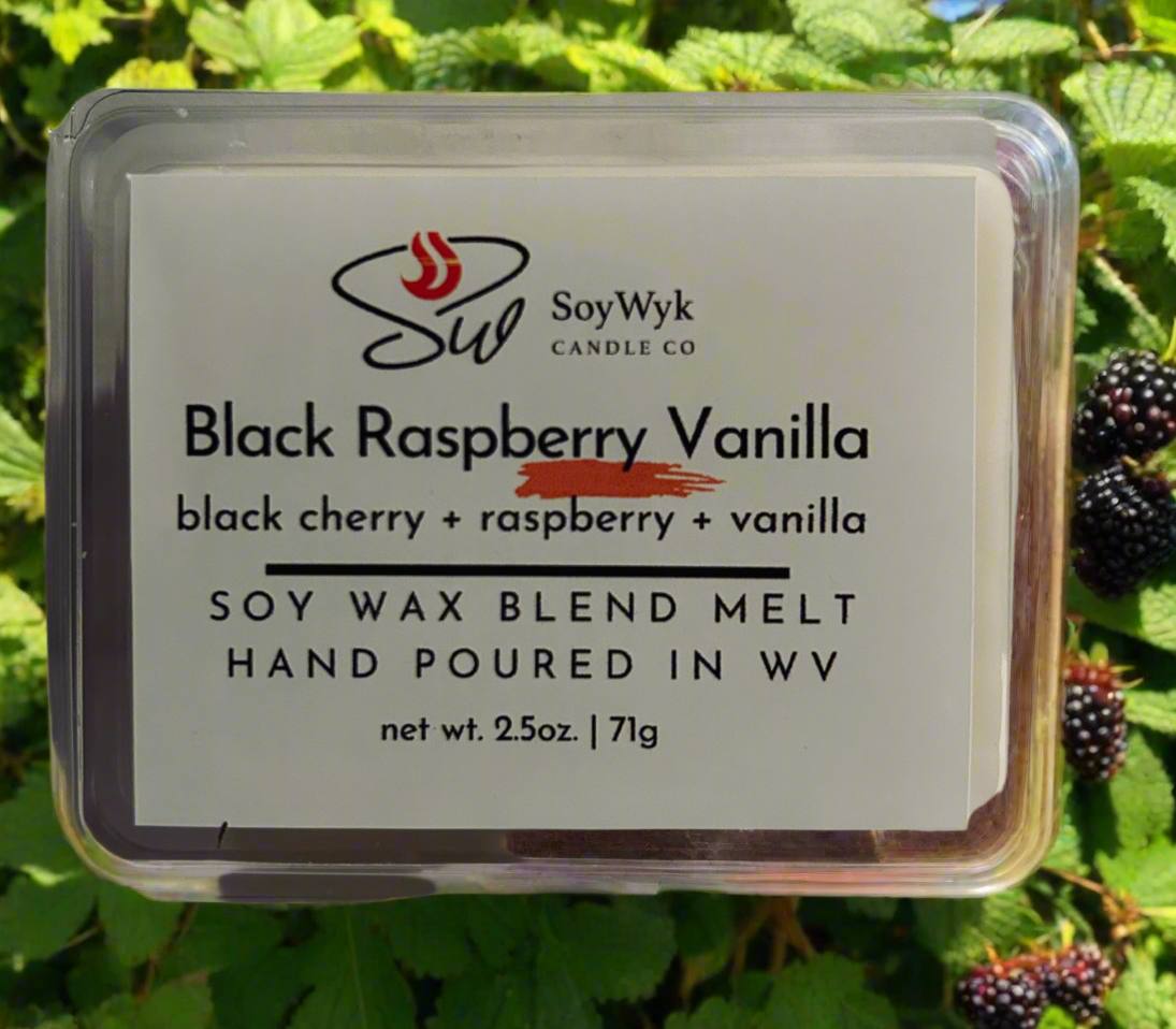 White Soy wax melt in 2.5 oz clear package labeled “Black Raspberry Vanilla” positioned in the middle of a blackberry bush.Featured  fragrant notes are black cherry, raspberry, vanilla. Hand-poured by  
Soywyk Candle Co in WV.