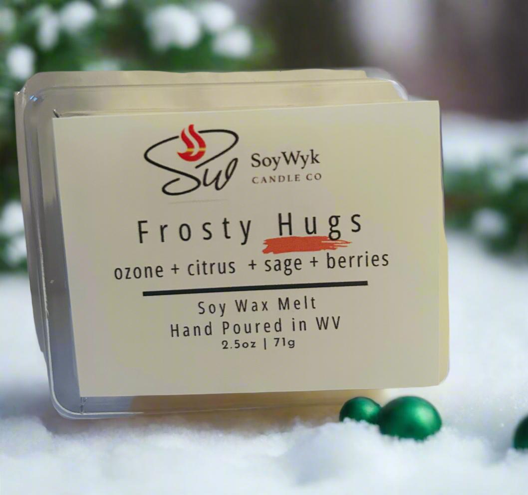 Soy wax melt in 2.5 oz clear package labeled “Frosty Hugs”. Featured fragrant notes are ozone, citrus, sage, berries sitting in a background of snow with green Christmas balls scatter around with pine tress in distance. Hand- poured by SoyWyk Candle Co in WV. 