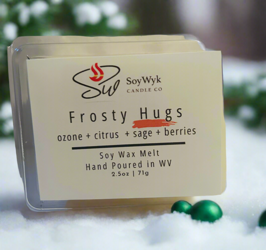 Soy wax melt in 2.5 oz clear package labeled “Frosty Hugs”. Featured fragrant notes are ozone, citrus, sage, berries sitting in a background of snow with green Christmas balls scatter around with pine tress in distance. Hand- poured by SoyWyk Candle Co in WV. 