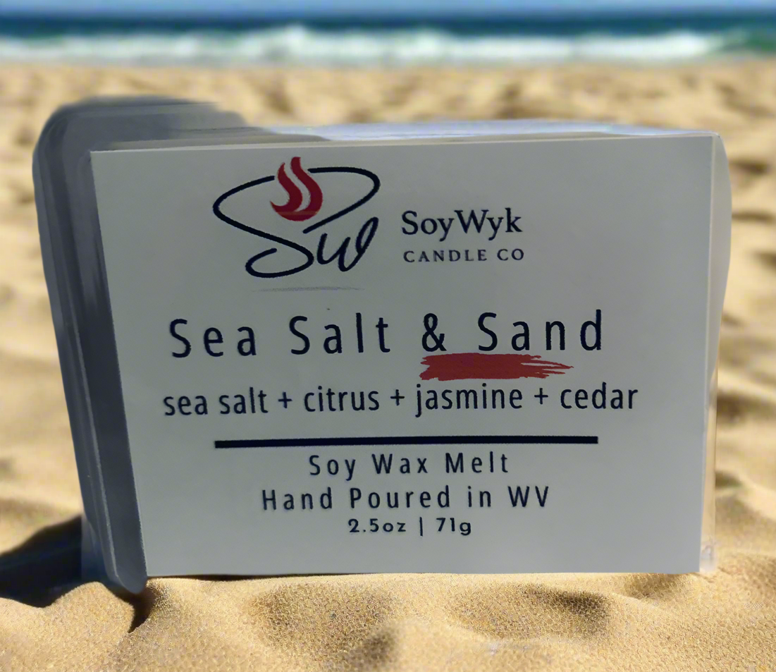 White Soy Wax Melt in a 2.5 oz clear package.  A bright sunny  day the wax melt is on a sandy beach with the blue green sea crashing waves behind them. Labeled as “ Sea Salt & Sand”. 
Featured fragrant notes are sea salt, citrus, jasmine, cedar
Hand-poured in WV by SoyWyk Candle Co. 