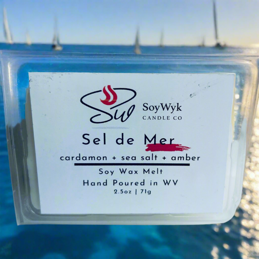 White Soy Wax Melt in a 2.5 oz clear package.  On a  sunny beach  the wax melt is on the sandy beach. You can see the ocean and several little sail boats just drifting out at sea. Labeled as “Sel de Mer”. 
Featured fragrant notes are cardamom, sea salt, amber 
Hand-poured in WV by SoyWyk Candle Co. 