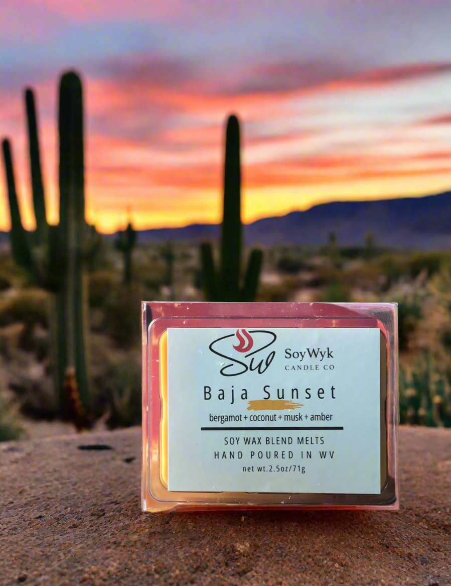 Light orange  Soy Wax Melt in a 2.5 oz clear package.  Wax melt  sitting on a large rock in the desert surrounded by several cactus and desert plants under an orange yellow sunset sky.  Labeled as “Baja Sunset”. 
Featured fragrant notes are bergamot, coconut, musk, amber 
Hand-poured in WV by SoyWyk Candle Co. 