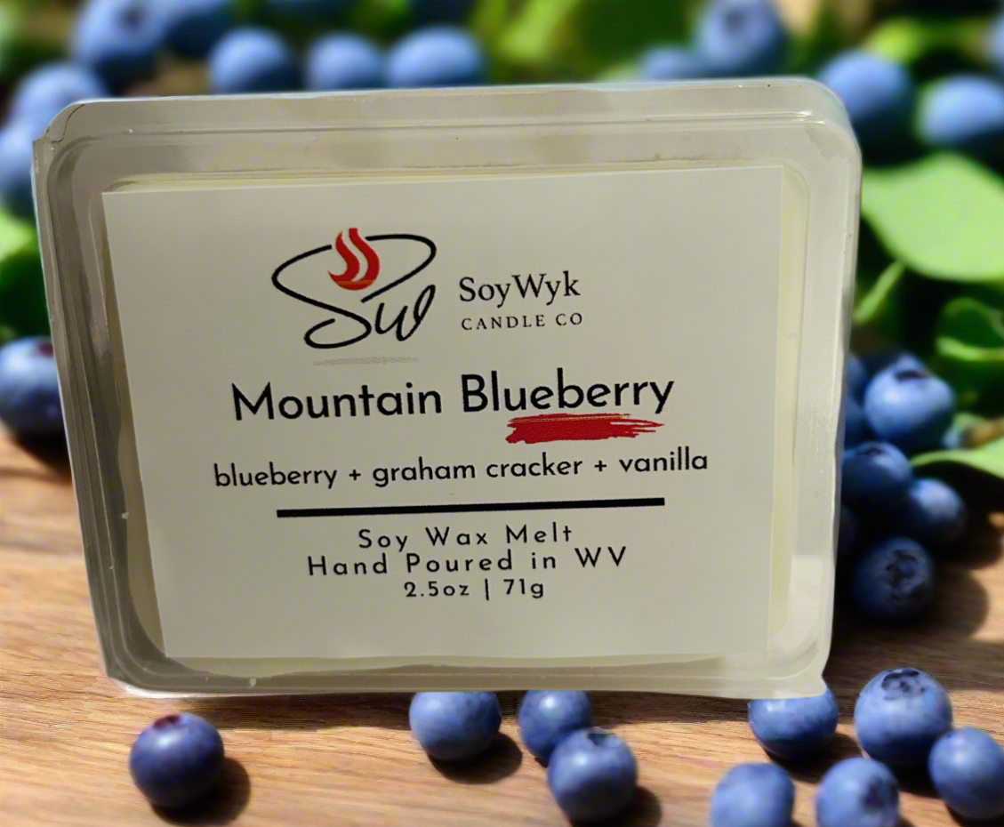 White Soy Wax Melt in a 2.5 oz clear package.  The wax melt is outside in the center of a wood table surrounded by blueberries and a few green leaves. Labeled as “Mountain Blueberry”
Featured fragrant notes are blueberry, graham cracker, vanilla 
Hand-poured in WV by SoyWyk Candle Co. 