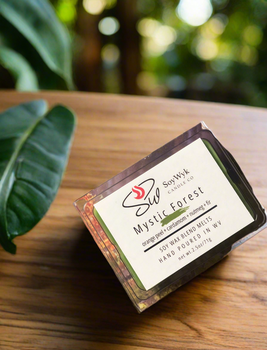 White Soy Wax Melt in a 2.5 oz clear package.  The wax melt is outside in the forest on a wood table surrounded by forest vegetation. Labeled as “Mystic Forest “. 
Featured fragrant notes are orange, cardamom, peppercorn, ginger, cinnamon, Fir
Hand-poured in WV by SoyWyk Candle Co. 