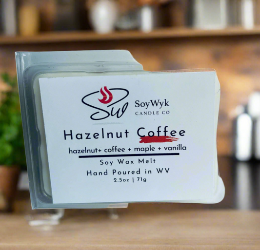 White Soy Wax Melt in a 2.5 oz clear package. Wax Melt on a wood countertop in modern kitchen with dome plants in background. Labeled as “Hazelnut Coffee”. Featured fragrant notes are hazelnut, coffee, maple, vanilla
Hand-poured in WV by SoyWyk Candle Co. 