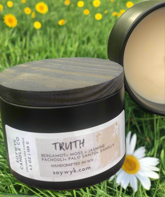 Coconut Soy Candle in a 5 oz modern black ceramic reusable jar with a wood lid labeled "Truth". Featured fragrance notes are bergamot, moss, jasmine, patchouli, palo Santo, vanilla on  a daisy covered Field background. One of the Signature Collections from Soywyk Candle Co. hand-poured in WV.