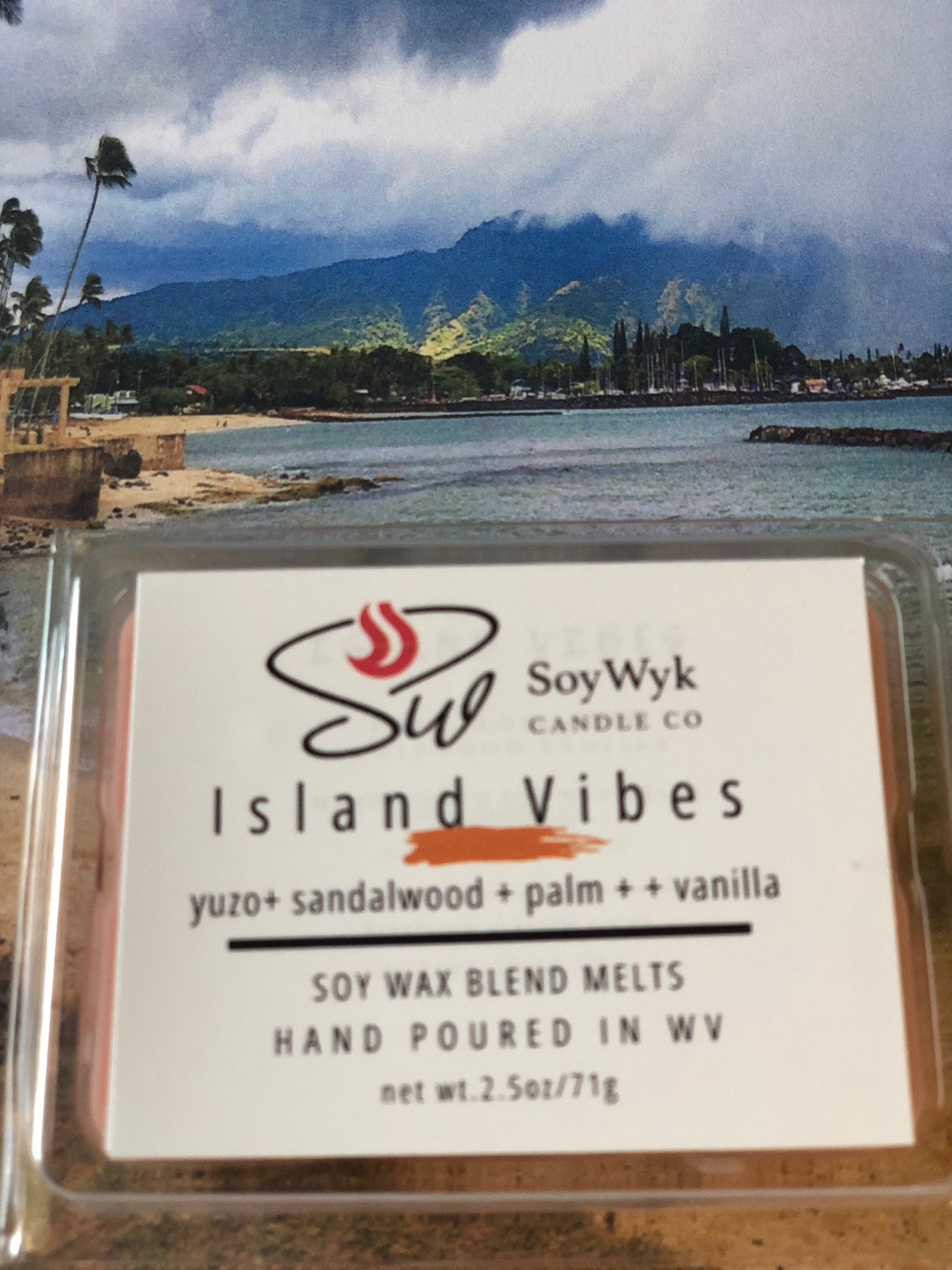 White Soy Wax Melt in a 2.5 oz clear package. Wax Melt against the beach coast can see the blue waters and mountains in the background. Labeled as “Island Vibes”. 
Featured fragrant notes are yuzo, sandalwood, palm, vanilla 
Hand-poured in WV by SoyWyk Candle Co. 