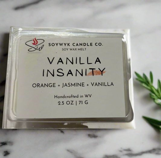 White Soy Wax Melt labeled “ Vanilla Insanity “ in a clear package Featured fragrant notes are orange, jasmine, vanilla. Pictured on a white ceramic countertop in a kitchen with a some greenery. Hand-poured in WV by SoyWyk Candle Co. 